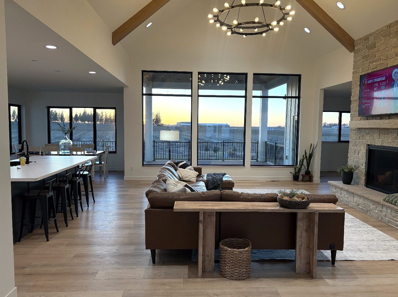 Vaulted great room with exposed beams, a chandelier and a stone fireplace