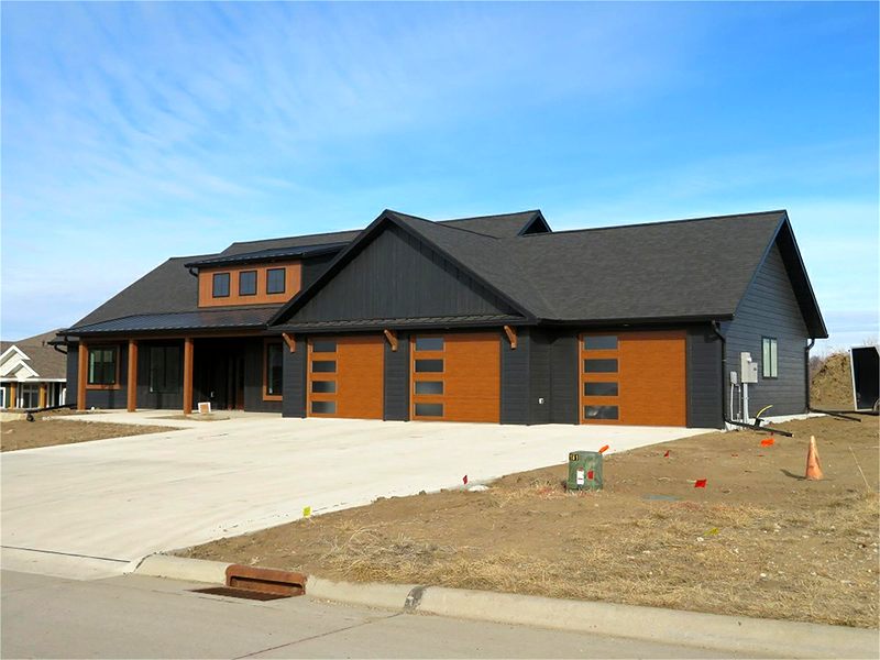 Charcoal board-and-batten home with cedar-tone garage doors