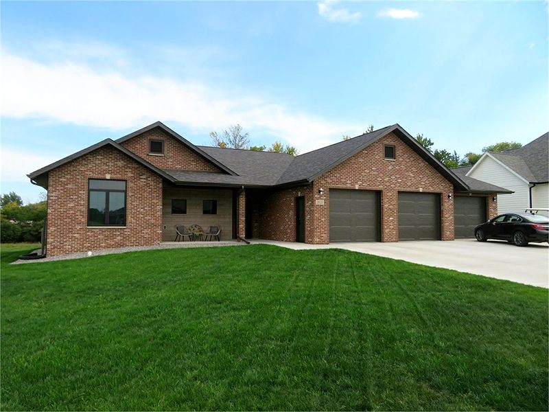 Brick ranch home with a three-stall garage and a green lawn