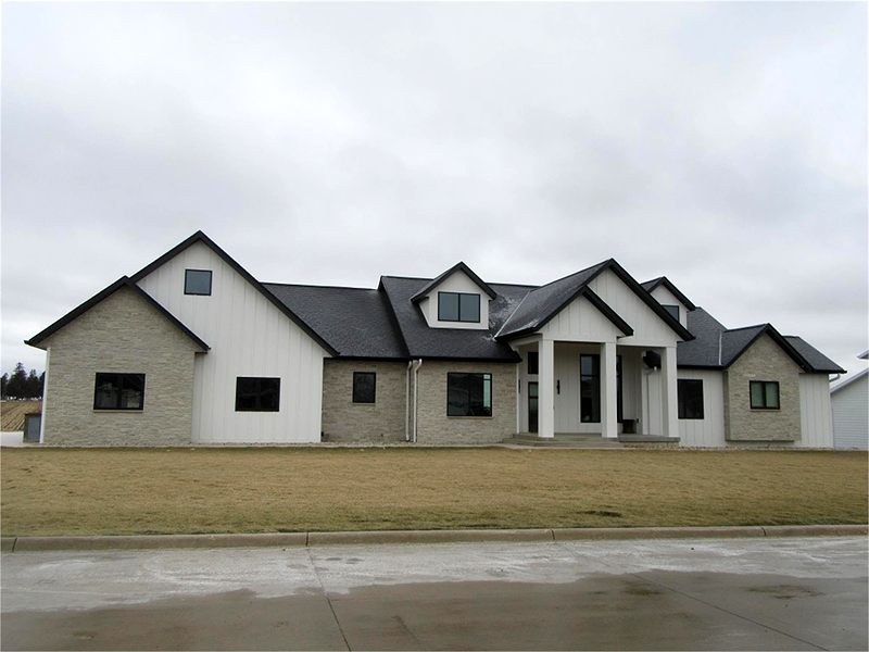 White and stone home with a gabled entry