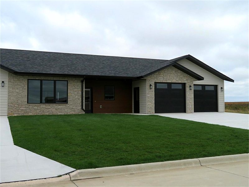 Ranch home with a stone front and black garage doors