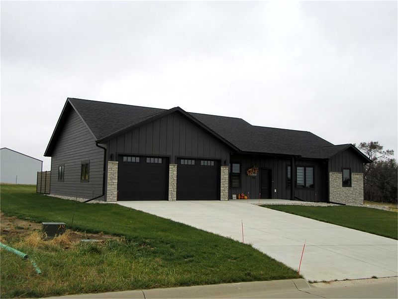 Dark board-and-batten ranch with stone accents