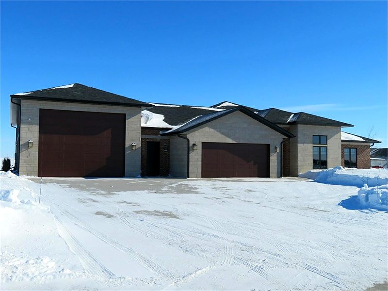 Two-tone home with brown garage doors after a snowfall