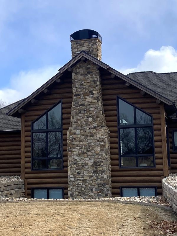 Stone chimney on a log-sided home